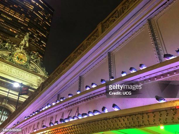 Pershing Square Plaza bridge with roosting pigeons and Grand Central Terminal at night with MetLife building behind, Manhattan, New York.