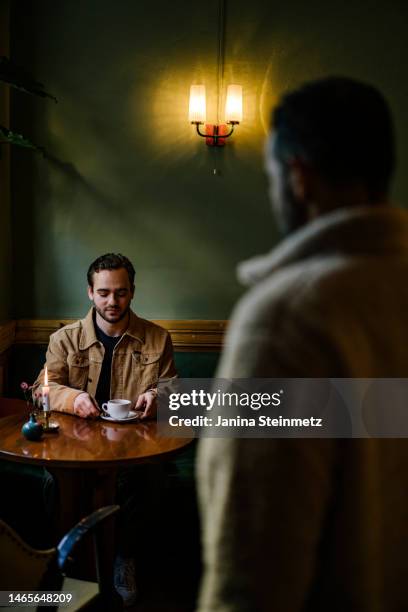 man waiting for date to arrive at cafe - approaching stock pictures, royalty-free photos & images
