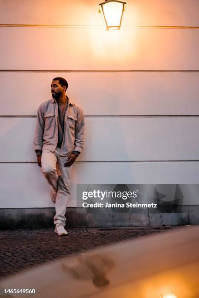 full length of stylish man leaning against building at night - mixed race person stock pictures, royalty-free photos & images