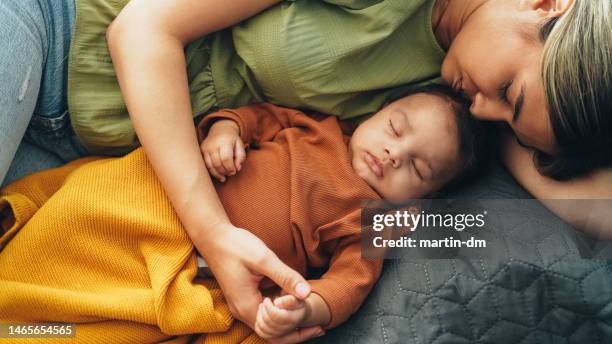 young mother and baby napping at home - hug sleep woman stock pictures, royalty-free photos & images