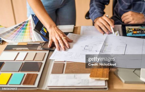close-up of a architect discussing building blueprints with female colleague in office - decorator stock pictures, royalty-free photos & images