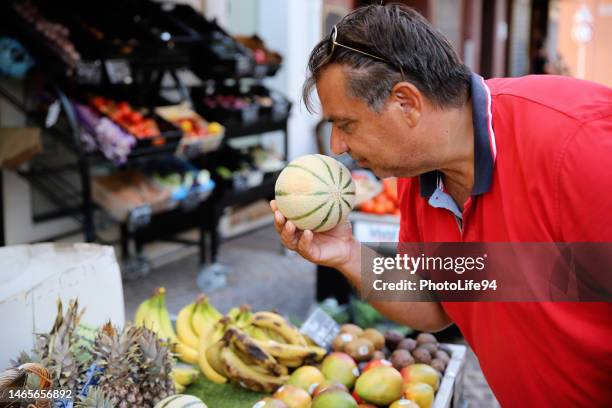 man choosing fresh fruit at the local market place - chef smelling food stockfoto's en -beelden