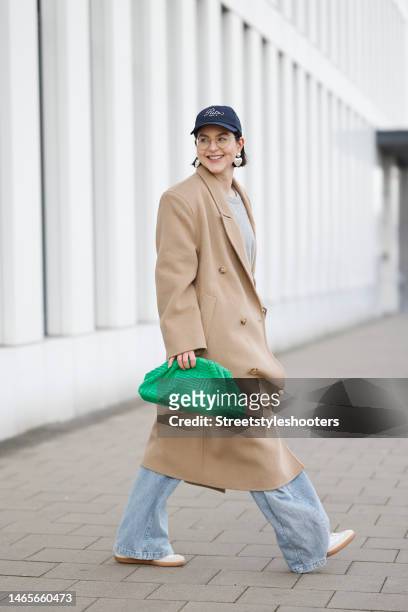 Influencer Maria Barteczko, wearing a beige camel oversized coat by The Frankie Shop, a grey wool sweater by Arket, blue high waisted baggy jeans by...
