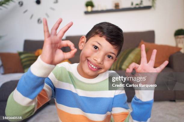 cheerful latin american boy looking at camera gesturing ok with two hands - agree stock pictures, royalty-free photos & images