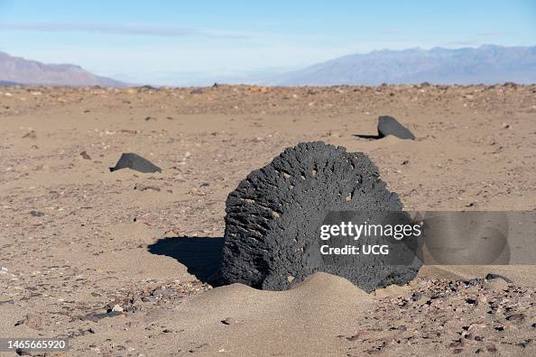 Ventifact and sand, a wind-and-sand eroded rock, Death Valley ...