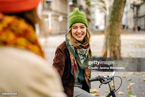 young adult female smiling at friend on city street - city life authentic stock pictures, royalty-free photos & images