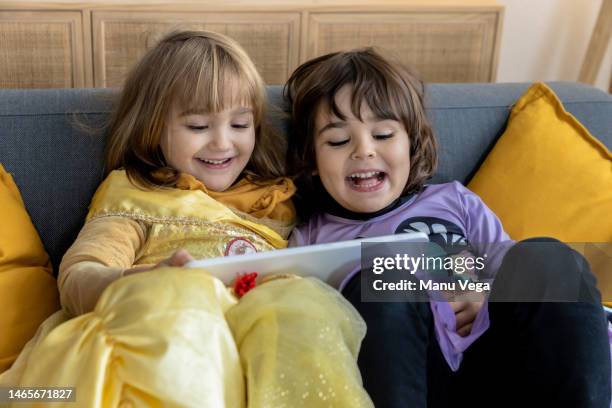 two girls having fun and smiling while using a digital tablet at home. - sister act stock pictures, royalty-free photos & images