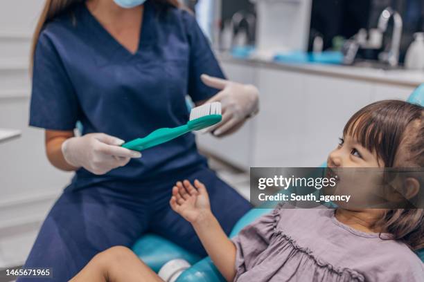 dentist explaining how to brush teeth - dentist's chair stock pictures, royalty-free photos & images