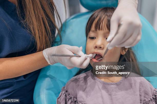 female dentist examining girl's teeth - tandpijn stockfoto's en -beelden