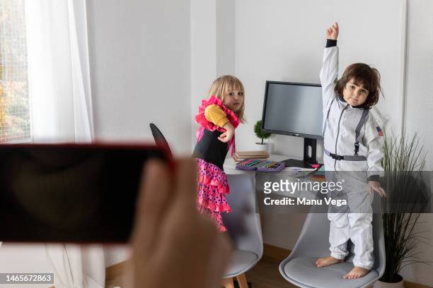 mother photographing with a mobile phone her children in costumes at home. - astronaut hand stock pictures, royalty-free photos & images