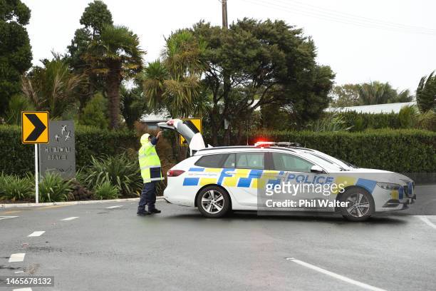 Police attend a roadblock limiting access to Muriwai Beach after the area suffered several landslides on February 14, 2023 in Auckland, New Zealand....