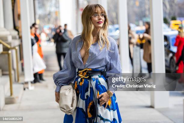 Julianne Hough wears high waisted belted blue skirt with floral print, white bag, stripped button shirt outside Carolina Herrera during New York...