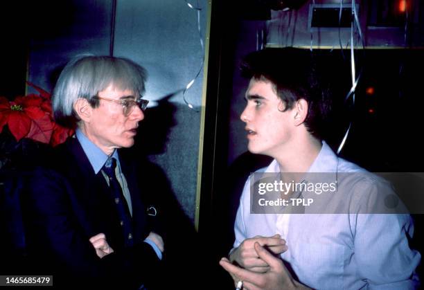 American visual artist, film director, and producer Andy Warhol talks with American actor Matt Dillon in New York, New York, December 1982.