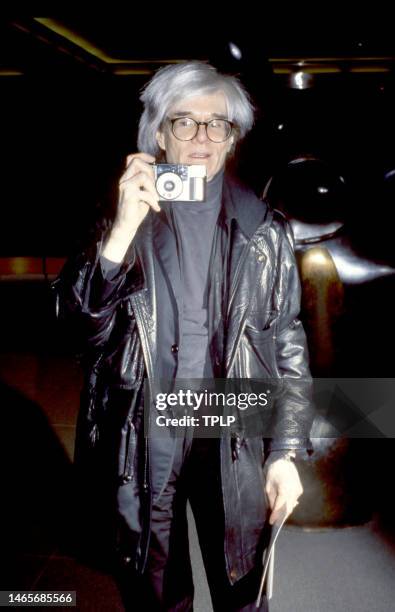 American visual artist, film director, and producer Andy Warhol poses for a portrait with his camera in New York, New York, circa 1986.