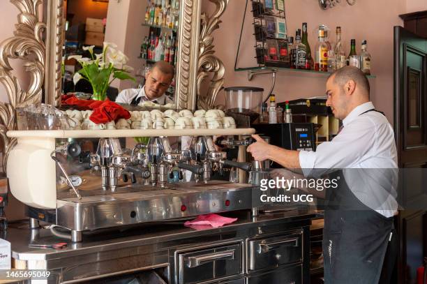 Barista using espresso coffee machine in cafe, Sassari, Sardinia, Italy.