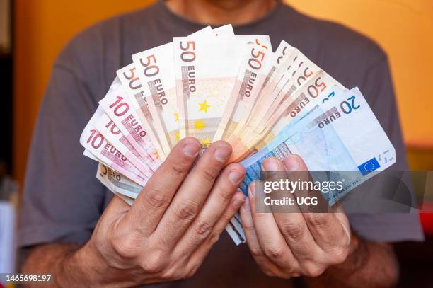 Man holding a lot of Euro bills in his hands.