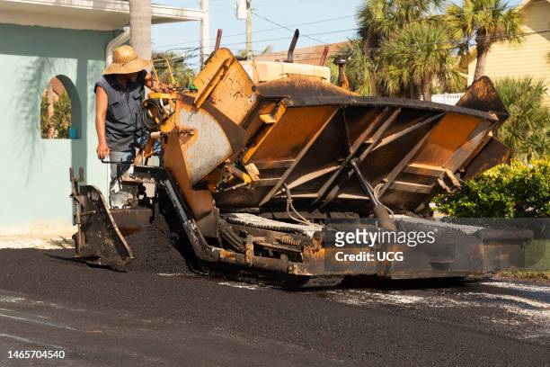 Cocoa Beach, Florida, Asphalting worker applying tarmac from a asphalt paver machine to resurface a Florida driveway.