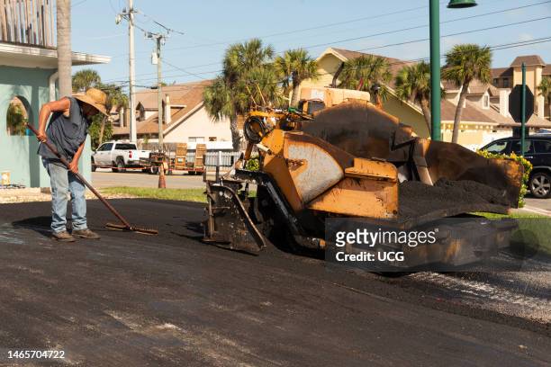 Cocoa Beach, Florida, Asphalting worker applying tarmac from a asphalt paver machine to resurface a Florida residential driveway.
