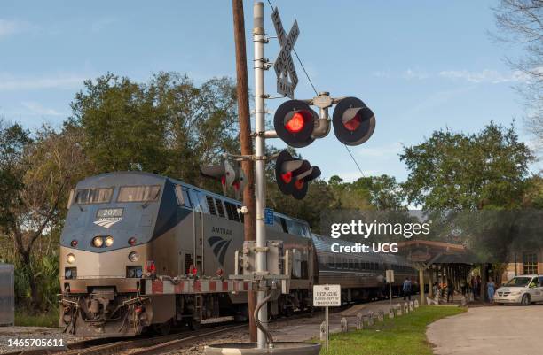 DeLand Florida, An Amtrak passenger train leaving DeLand Station , Florida at a level crossing with red lights.