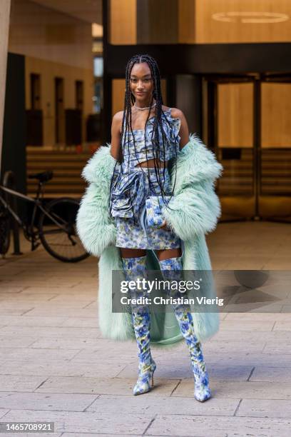 Cheyenne Maya Carty wears blue cut out dress with floral print, over knees boots, faux fur coat outside Carolina Herrera during New York Fashion Week...