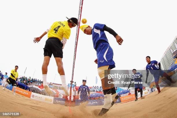 Komkid Suapimpa of Thailand heads over the net against Dong Han of China during the Beach Sepaktakraw Men's Regu Preliminary match between Thailand...