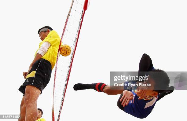 Uthen Kukheaw of Thailand kicks over the net against Dong Han of China during the Beach Sepaktakraw Men's Regu Preliminary match between Thailand and...