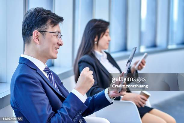 men excitement looking at digital tablet, woman colleague sitting at distance - cas awards stock pictures, royalty-free photos & images