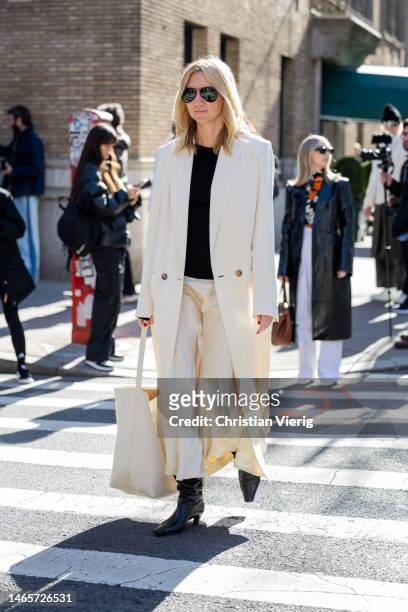 Lisa Aiken wears white coat, pants, bag outside Coach during New York Fashion Week on February 13, 2023 in New York City.
