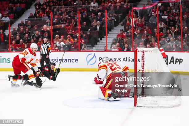 Tim Stützle of the Ottawa Senators scores the overtime game winning goal against Jacob Markstrom of the Calgary Flames as his teammate MacKenzie...