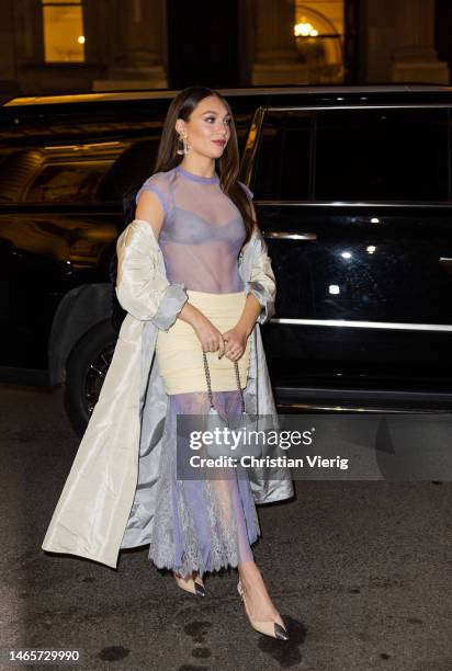 Maddie Ziegler wears purple see trough dress, beige skirt, grey coat, bag outside Tory Burch during New York Fashion Week on February 13, 2023 in New...