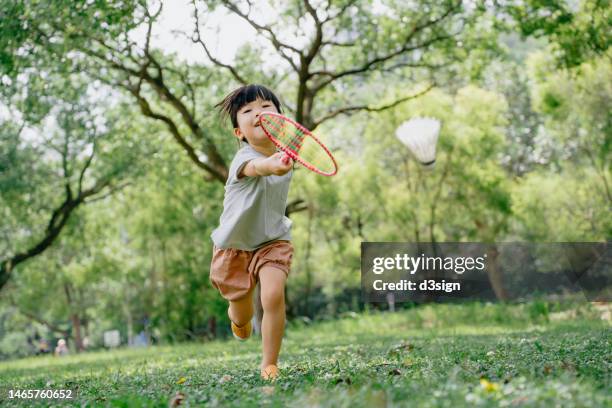 little asian girl having fun playing badminton in park on a beautiful sunny day. outdoor fun activity concept - shuttlecock 個照片及圖片檔