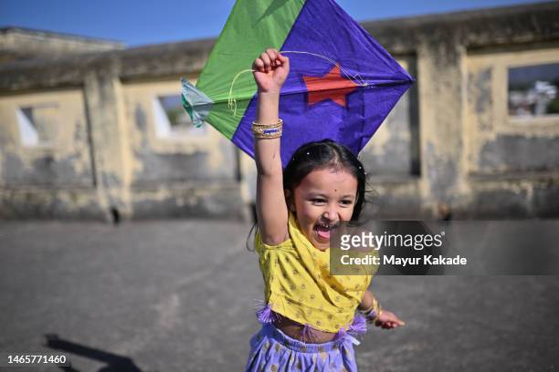 picture of a cute laughing girl running with a kite on the terrace celebrating makar sankranti - kite toy stock-fotos und bilder
