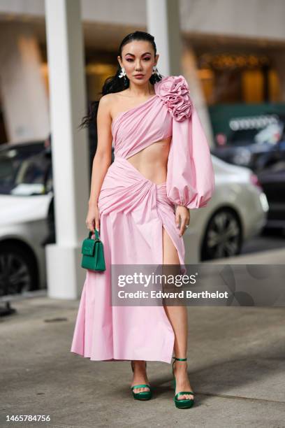 Jessica Wang wears white flower and pendant green earrings, a pale pink asymmetric shoulder / asymmetric one long sleeves / embroidered flower on the...