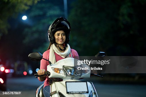 Happy woman riding motorcycle with helmet at night Happy woman riding motorcycle with helmet at night