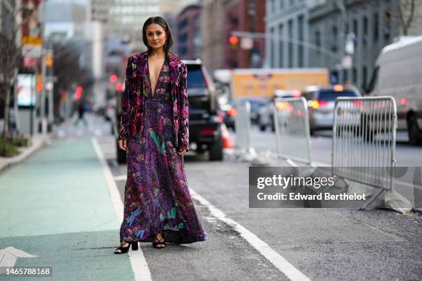 Guest wears black pendant earrings, a dark multicolored V-neck / long dress with embroidered pearls pattern, a black with pink and purple embossed...