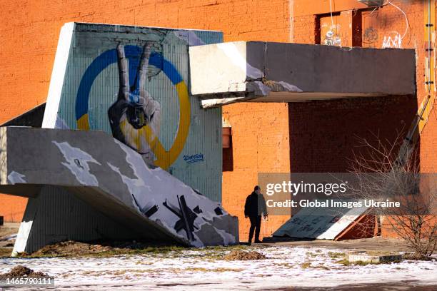 Man stands at a mural depicting the peace sign and the peace symbol in the colors of Ukrainian flag on February 9, 2023 in Kyiv, Ukraine. Russian...