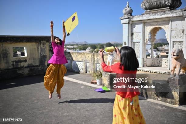 two cute girls flying kite on the terrace celebrating makar sankranti festival - indian kite festival stock pictures, royalty-free photos & images