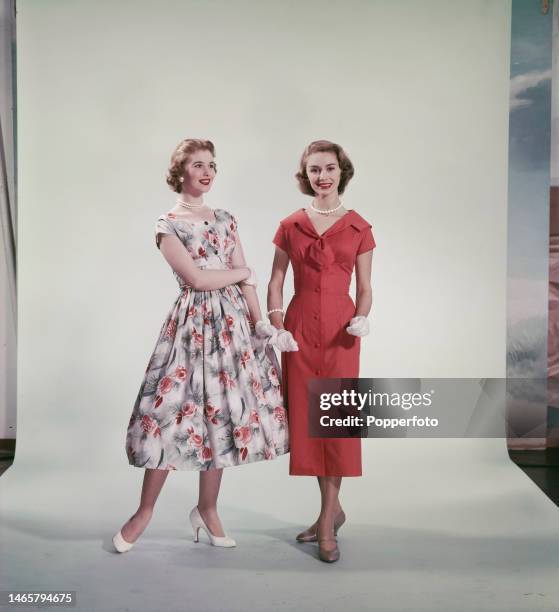 Posed studio portrait of two women wearing summer dresses, one features a rose print with a full skirt and the other is a slim fitting style with a...