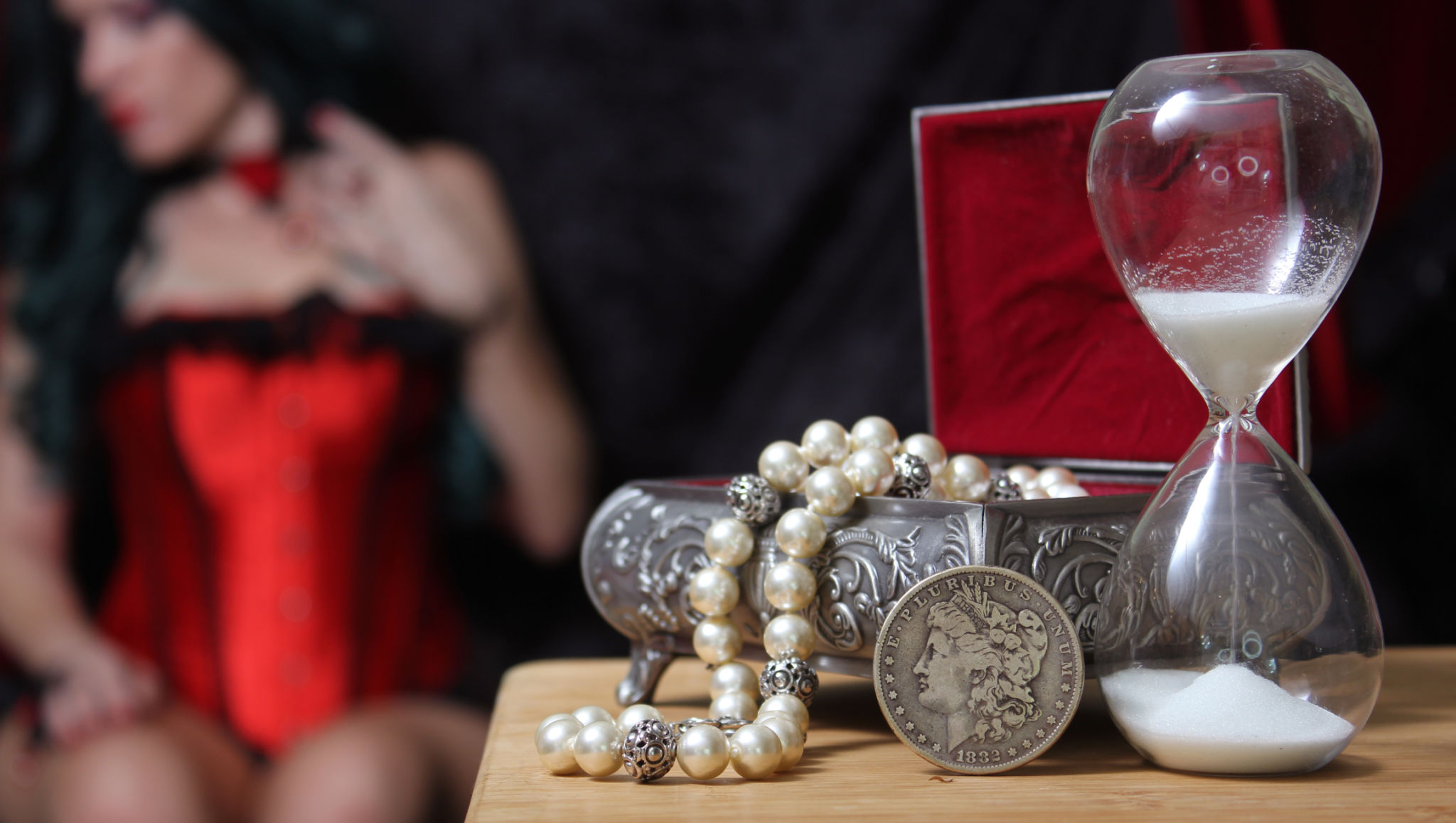 Selective of a vintage jewelry box with hourglass on the background of a female in red corset Selective of a vintage jewelry box with hourglass on the background of a female in red corset