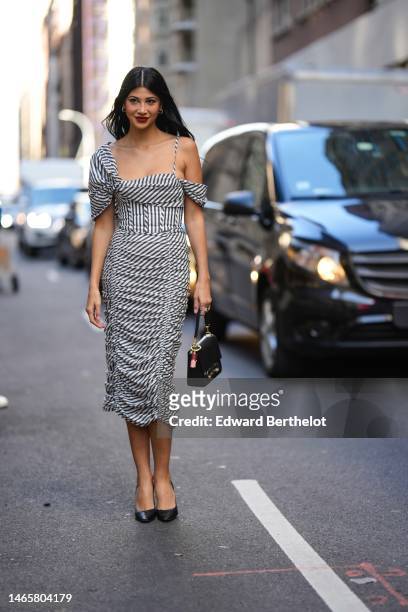 Guest wears silver and diamonds earrings, a black and white striped print pattern asymmetric short shoulders / square neck / midi tube dress, a black...