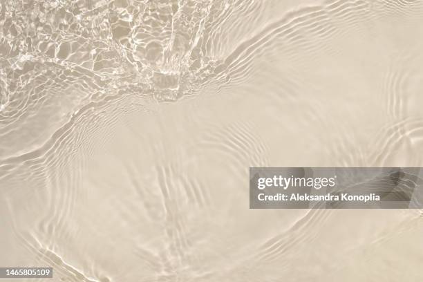 light pastel cream pink, grey beige transparent clear water surface texture with ripples, splashes and waves in sunlight - water surface stock pictures, royalty-free photos & images