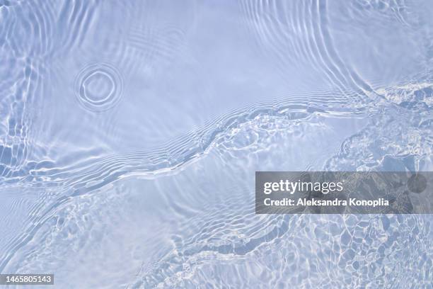 light pastel blue transparent clear water surface texture with ripples, splashes and waves in sunlight - wasseroberfläche stock-fotos und bilder