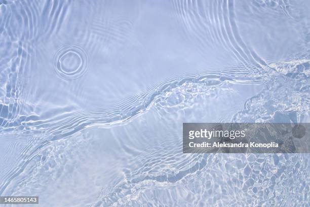 light pastel blue transparent clear water surface texture with ripples, splashes and waves in sunlight - superfície de água - fotografias e filmes do acervo