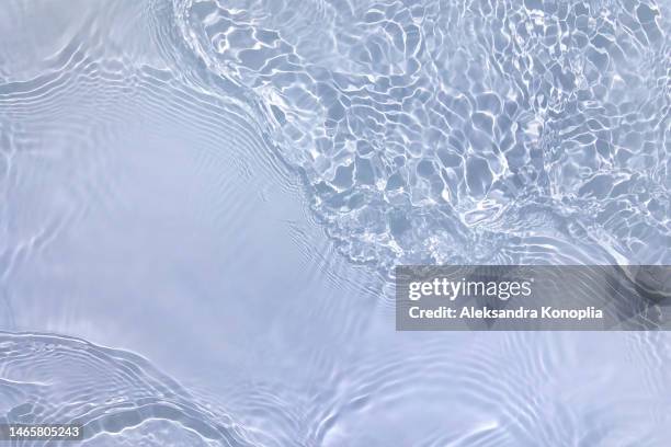 light pastel blue transparent clear water surface texture with ripples, splashes and waves in sunlight - transparent photos et images de collection
