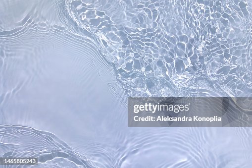 Light pastel blue transparent clear water surface texture with ripples, splashes and waves in sunlight Light pastel blue transparent clear water surface texture with ripples, splashes and waves in sunlight