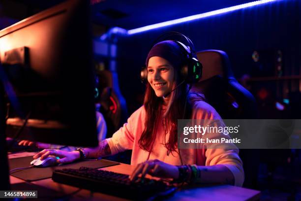 happy female gamer playing esports over desktop pc in entertainment club. - game streamer stock pictures, royalty-free photos & images