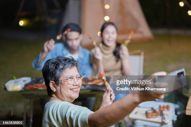 asian family takes a selfie during a dining barbecue at camping - reünie sociaal stockfoto's en -beelden