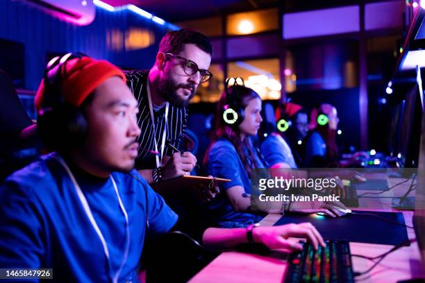 male judge writing scores during an esports tournament in gaming club. - judge entertainment stock pictures, royalty-free photos & images