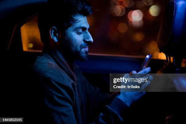 happy man using mobile phone on back seat of car - smartphone dark stock pictures, royalty-free photos & images