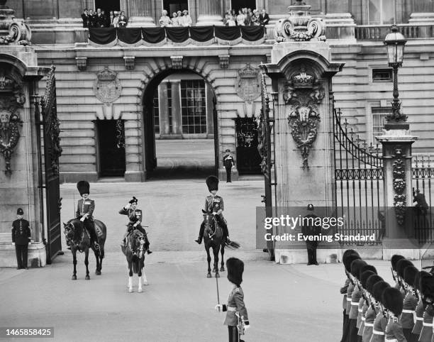 High angle view of British Royals Queen Elizabeth II, wearing a Guards Regiment uniform and biretta, and Prince Philip, Duke of Edinburgh, wearing a...